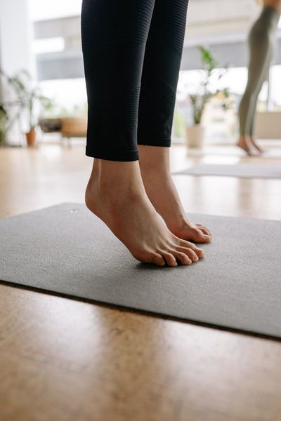 Close-up of feet on a yoga mat performing a balancing pose.